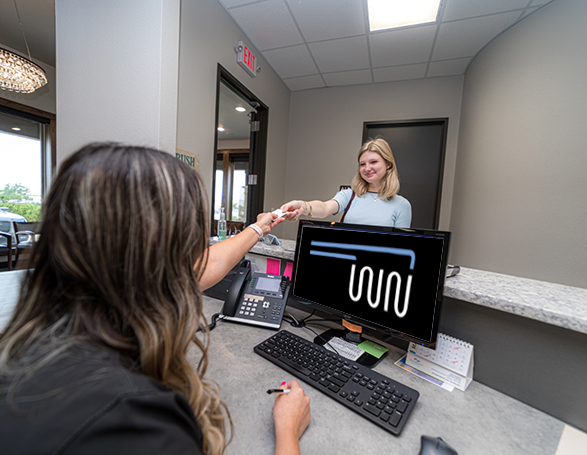 Woman handing a card to a dental office receptionist