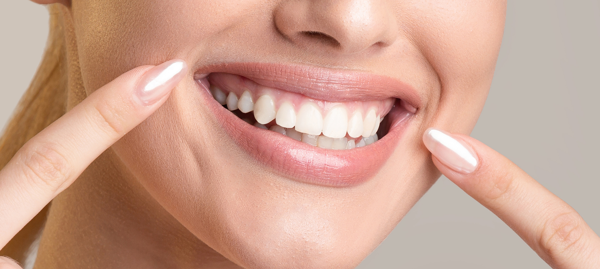 Smiling person pointing to their flawless teeth after cosmetic dentistry in College Station